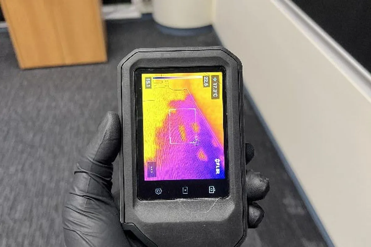 Thermal imaging camera showing a moisture heat map on a wall