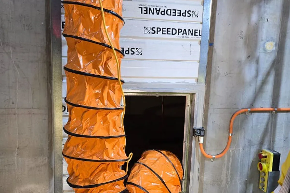 Orange ventilation duct connected through the wall panel