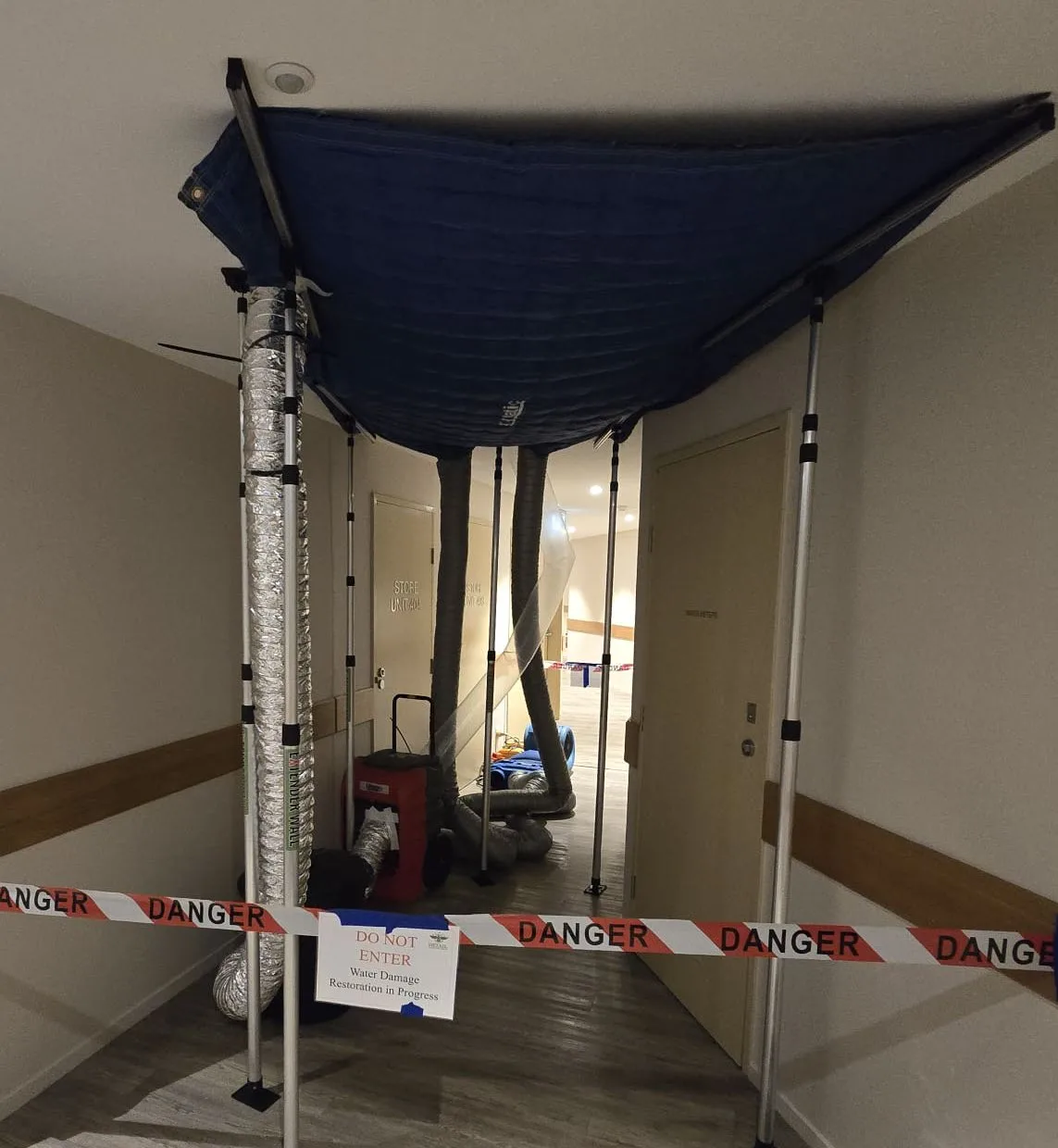 Containment and drying setup installed under an affected ceiling in a common corridor