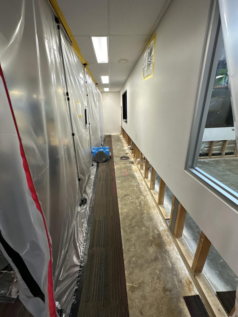 HEPA containment corridor with plastic sheeting and air mover during daily moisture monitoring at the Dromana school restoration
