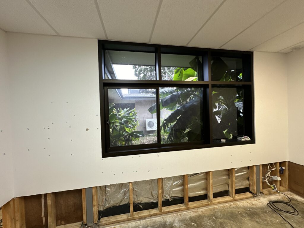 Exposed wall framing below a classroom window after strip-out, ready for the structural drying and monitoring phase