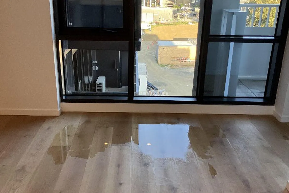 Water pooled on flooring beside a balcony door