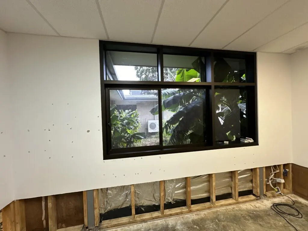 Exposed wall framing below a classroom window after strip-out, ready for the structural drying and monitoring phase